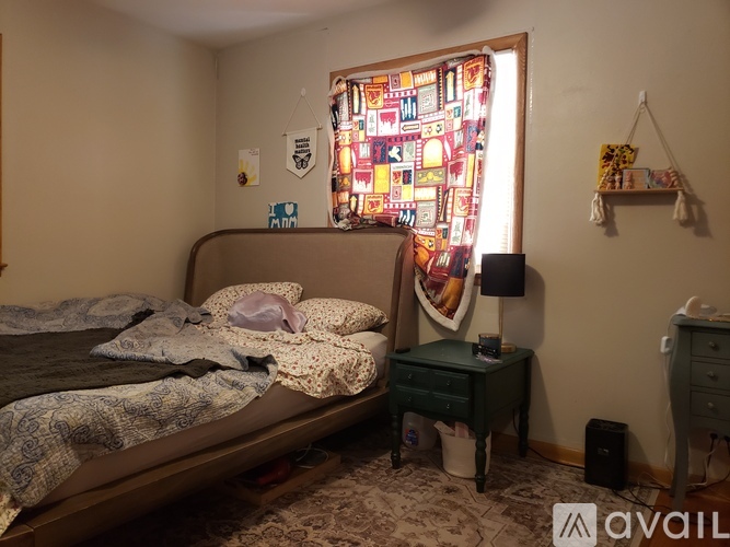 A bedroom with a bed, a nightstand, and a window with a colorful stained glass design.