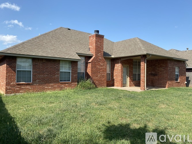 A house with a brown roof and brick walls is surrounded by a grassy area.