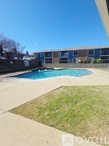 A swimming pool in a backyard with a building in the background.