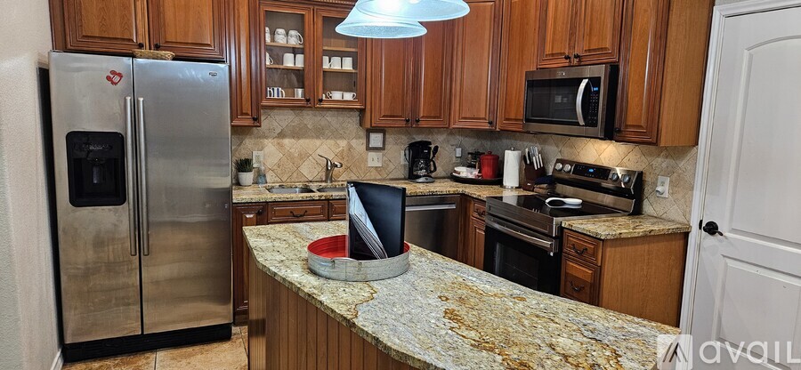 A kitchen with a granite counter top and stainless steel appliances.