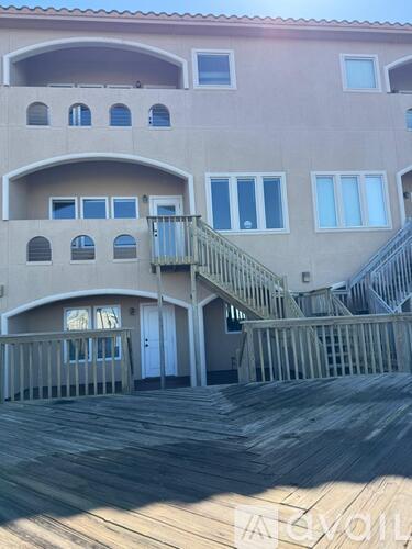 A wooden deck leads to a staircase on a building.