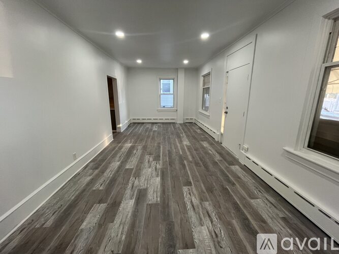 A room with wooden flooring and white walls.