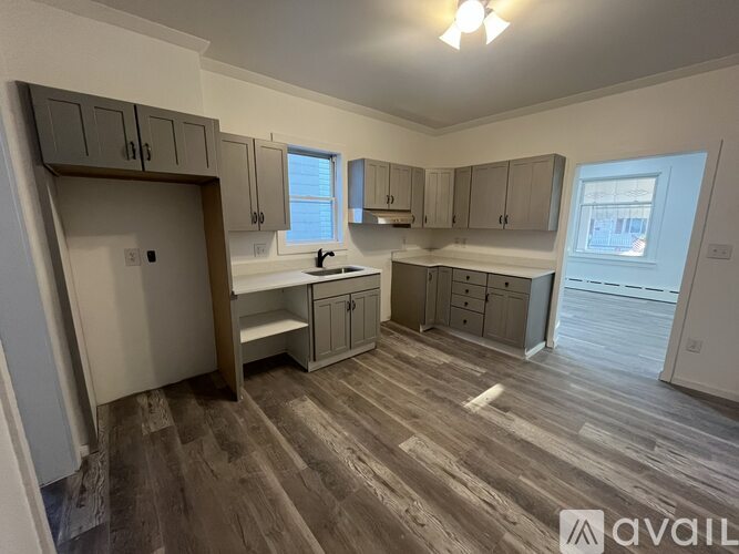 A kitchen with wooden floors and grey cabinets is available for rent.