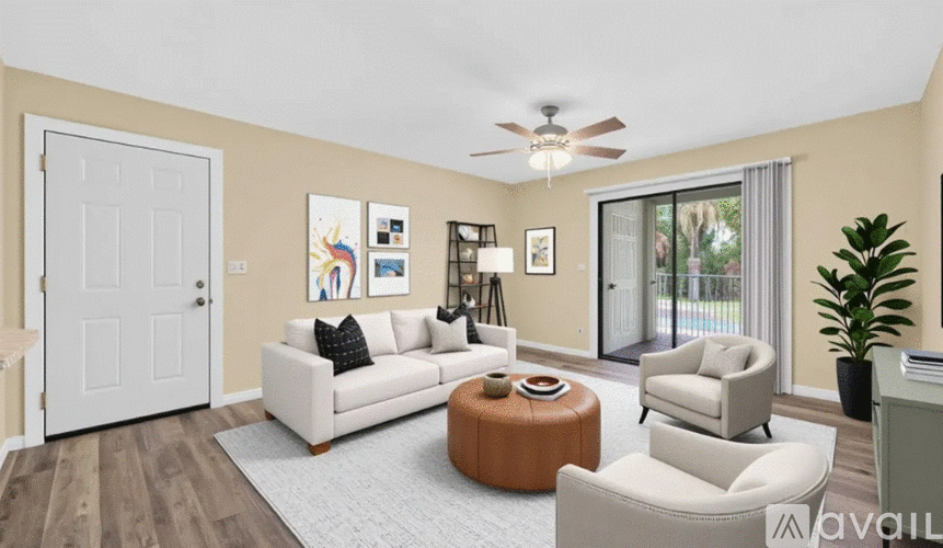 A living room with a white couch, a brown ottoman, and a ceiling fan.