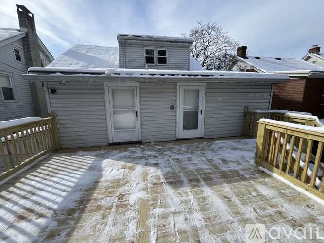 A house with a snow-covered roof and a deck in front.