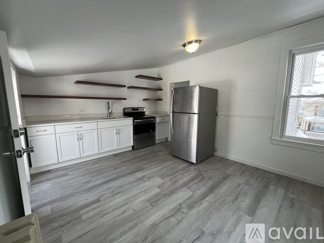 A kitchen with white cabinets and a stainless steel refrigerator.