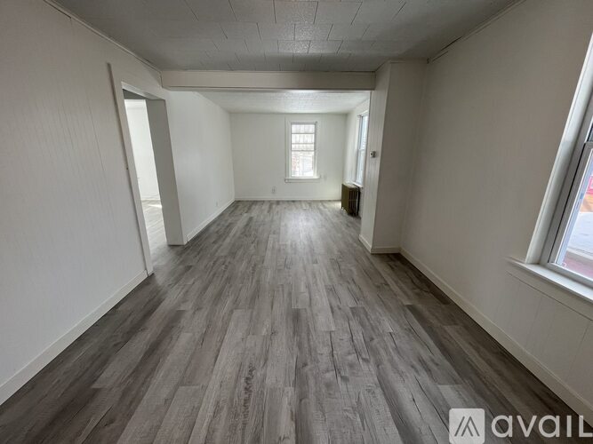 A spacious room with wooden flooring and white walls.