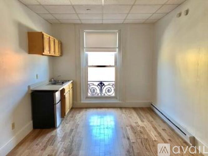 A small kitchen with wooden floors and a window with a metal grill.