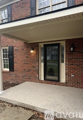 A red brick house with a white door and a small porch.
