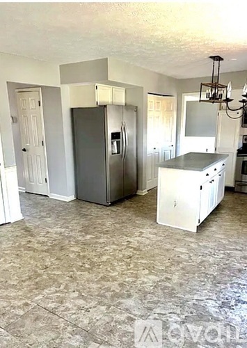 A kitchen with a refrigerator, a stove, and a chandelier.
