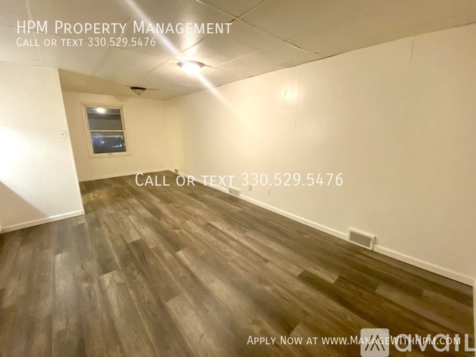 A room with wood flooring and a window, with text overlay advertising HPM Property Management.
