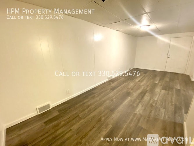 A room with wooden flooring and a white wall, with text overlay for HPM Property Management.