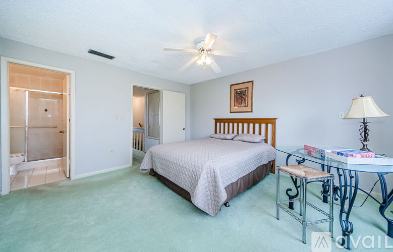 A bedroom with a bed, a chair, and a table with a lamp on it.