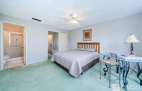 A bedroom with a bed, a chair, and a table with a lamp on it.