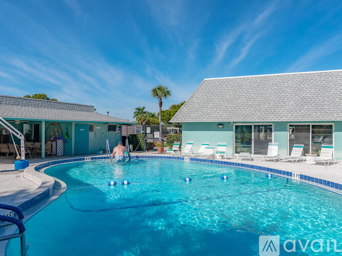 A man is swimming in a pool with a building in the background.