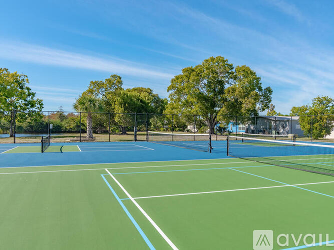 A tennis court with a blue and green surface surrounded by trees.