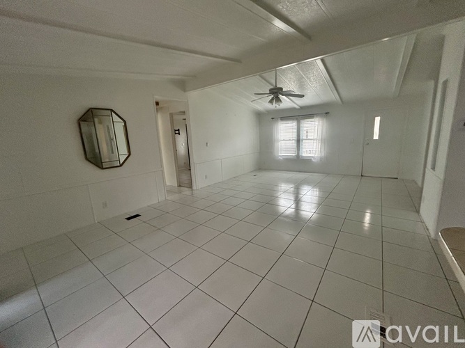 A spacious room with white tiled flooring and a ceiling fan.