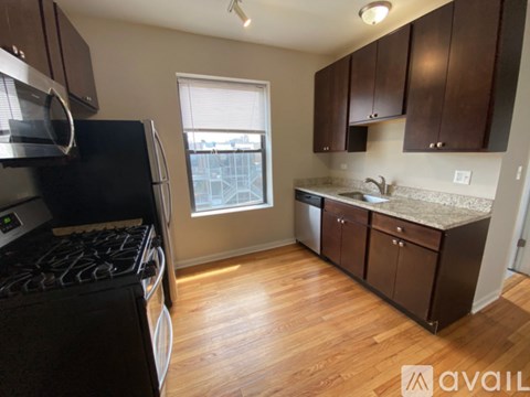 A kitchen with a black stove top oven and wooden flooring.