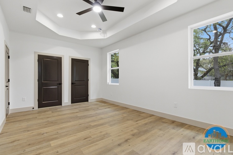 A spacious room with wooden floors and a ceiling fan.