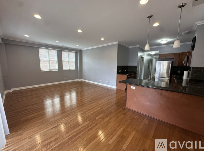 A spacious room with wooden floors and a kitchen area.