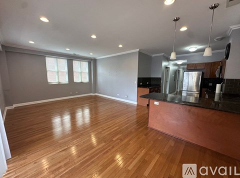 A spacious room with wooden floors and a kitchen area.