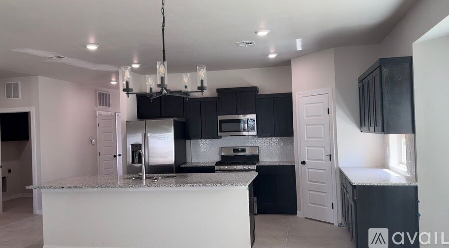 A kitchen with black cabinets and a white island.