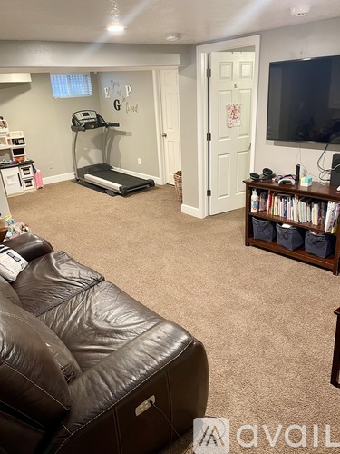 A living room with a brown leather couch and a treadmill.
