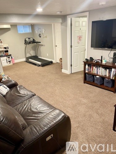 A living room with a brown leather couch and a treadmill.