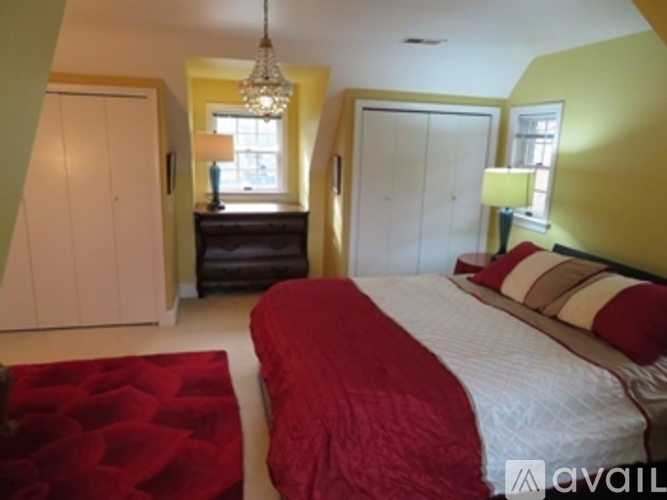 A bedroom with a red bedspread and a chandelier.