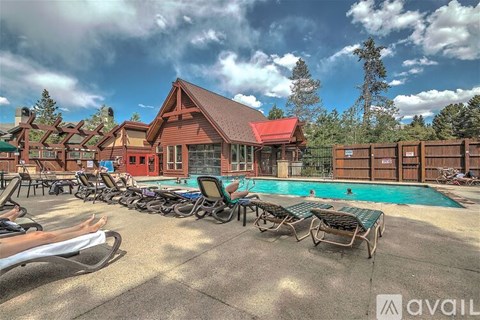 A pool area with sun loungers and a building in the background.