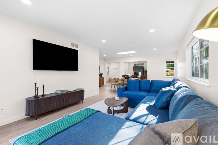 A living room with a blue couch and a television on the wall.
