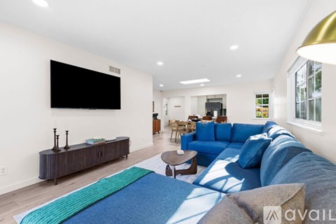 A living room with a blue couch and a television on the wall.