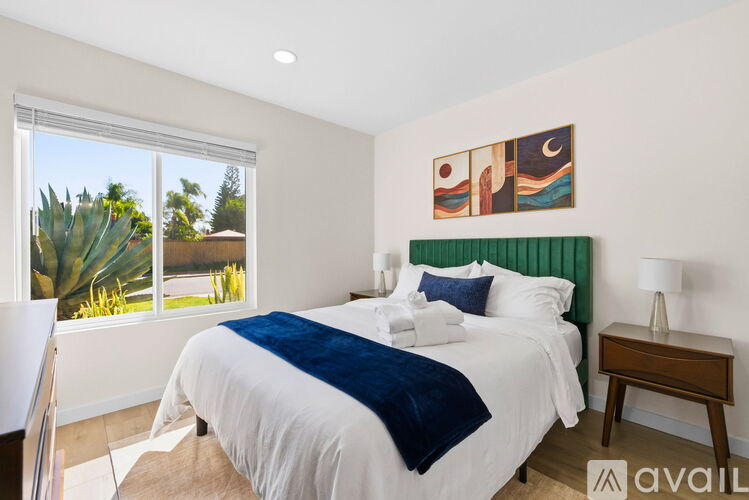 A bedroom with a large bed and a window overlooking a garden.