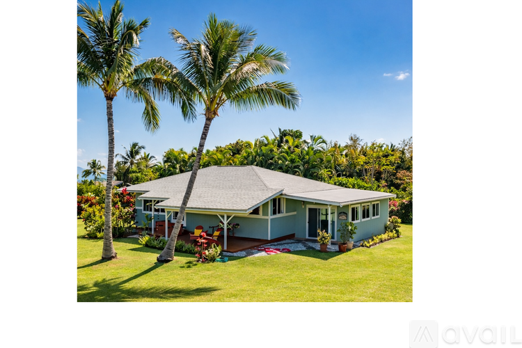 A house with a green lawn and palm trees in front.