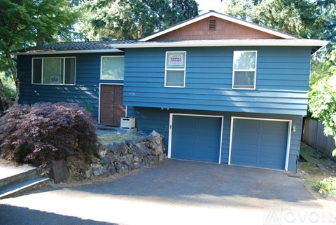 A blue house with a sign that says "For Sale" on the front.