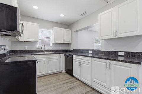 A kitchen with white cabinets and a black countertop.