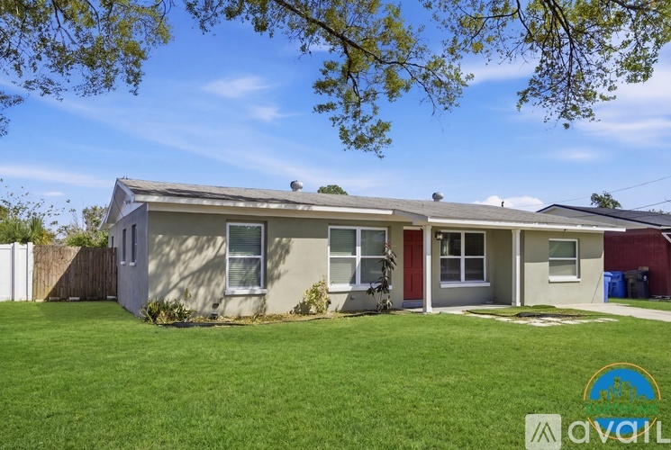 A house with a red door is surrounded by a green lawn.