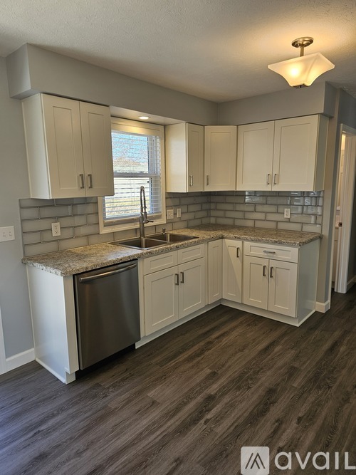 A kitchen with a granite countertop and wooden flooring.