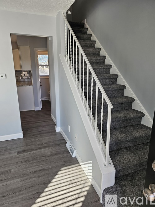 A staircase with a white railing and a grey carpeted runner.