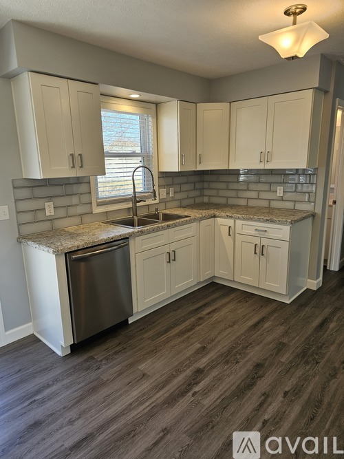 A kitchen with white cabinets and a wooden floor.