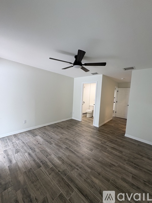 A room with a ceiling fan and wooden flooring.