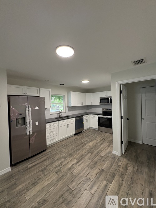 A kitchen with a refrigerator, sink, and cabinets.