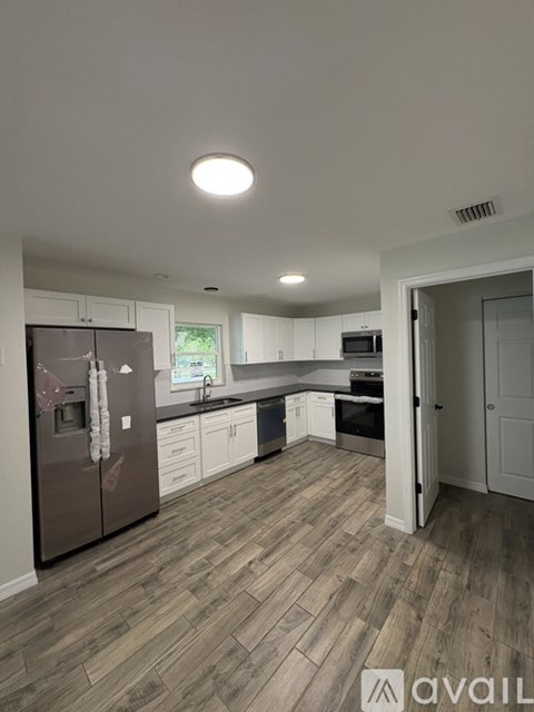 A kitchen with a refrigerator, sink, and cabinets.