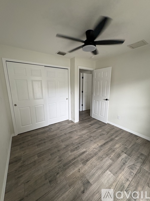 A room with a ceiling fan and two doors.