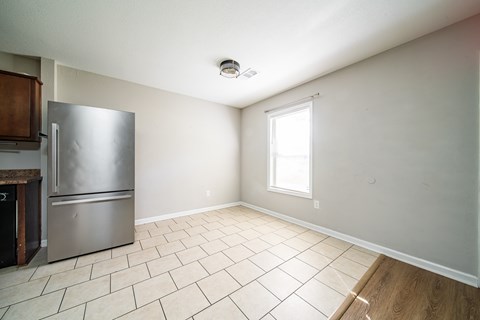 A kitchen with a stainless steel refrigerator and a window.