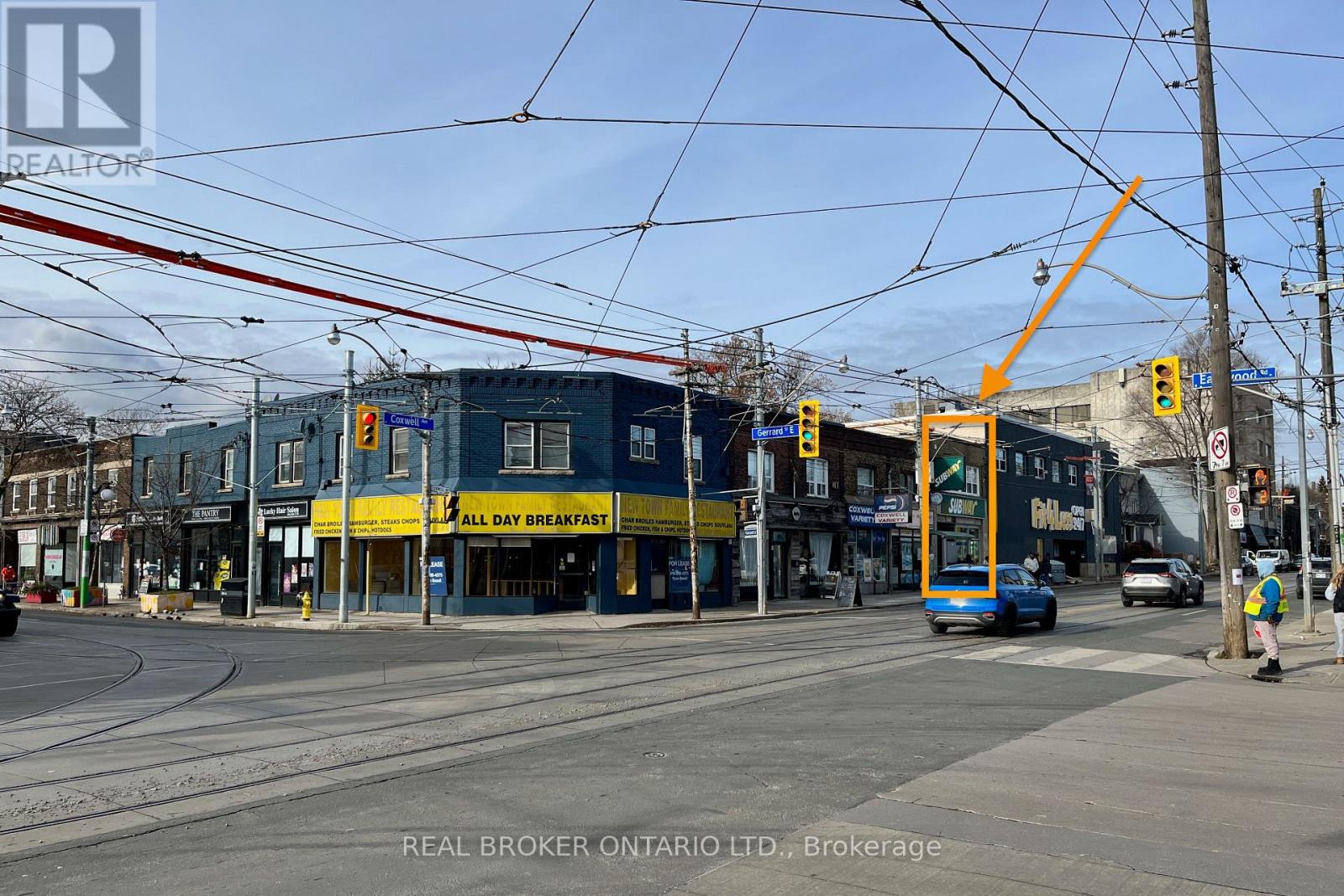 A street view with a blue bus and a yellow building with a sign that says "All Day Breakfast".