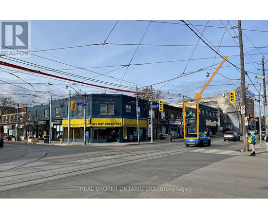 A street view with a blue bus and a yellow building with a sign that says "All Day Breakfast".