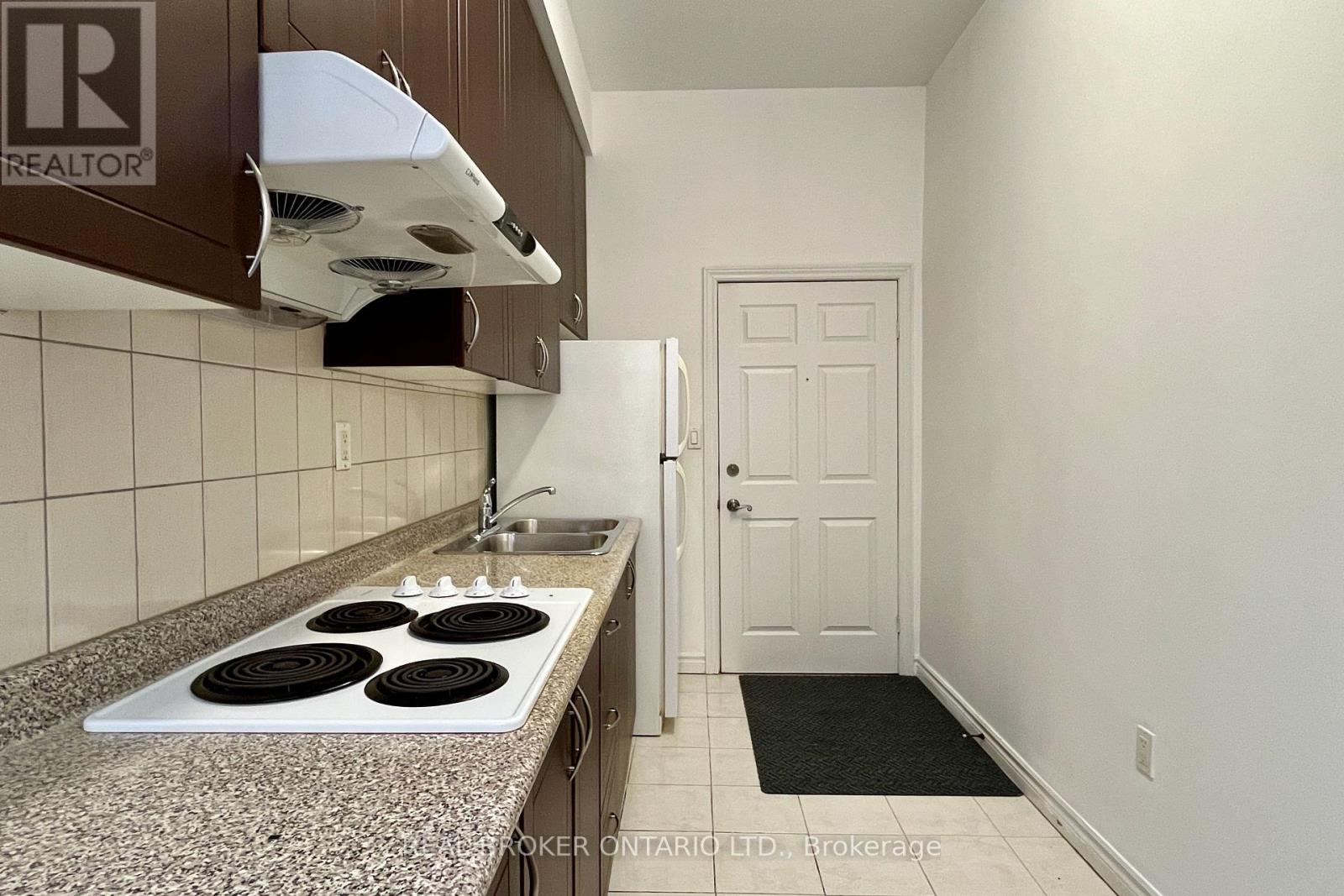 A kitchen with a stove top oven and a broker logo.