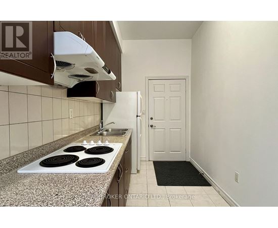 A kitchen with a stove top oven and a broker logo.