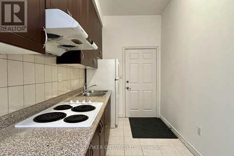 A kitchen with a stove top oven and a broker logo.